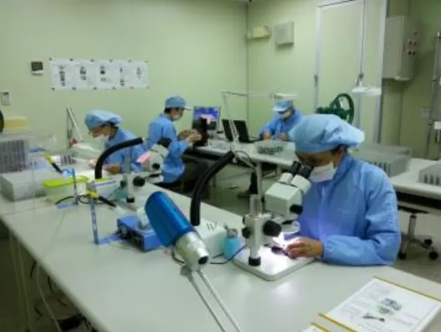 光學組裝區：穿無塵衣的作業員用顯微鏡組裝零件